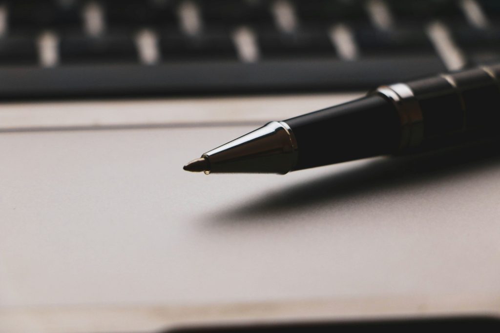 a pen sitting on top of a paper next to a keyboard